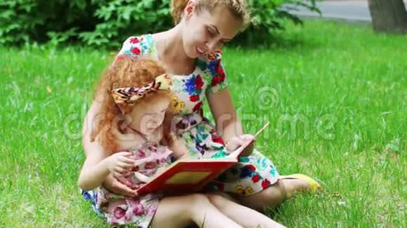 一个红头发的小女孩和她妈妈在草坪上看书视频的预览图