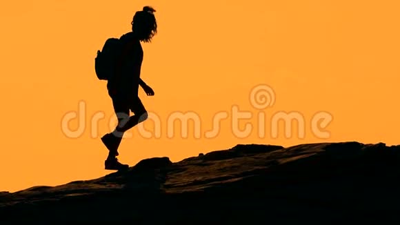 日落时分在山上行走的女孩的剪影视频的预览图