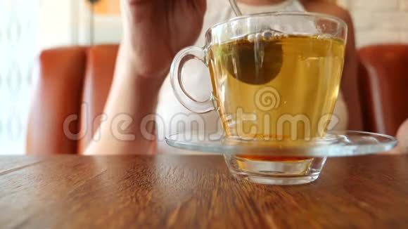 女孩把一块红糖放在一个透明的杯子里上面有绿茶气泡上升慢动作视频的预览图