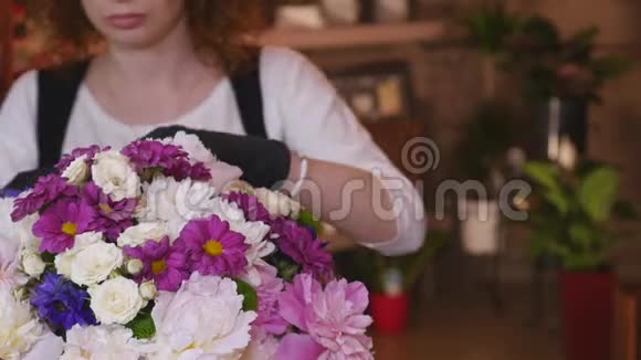 年轻女子在花店当花店花店工看着相机书桌上放着花束微笑视频的预览图