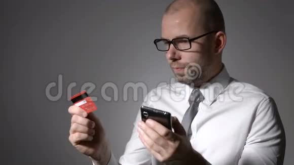 一个有胡子的商人拿着手机和信用卡的手视频的预览图