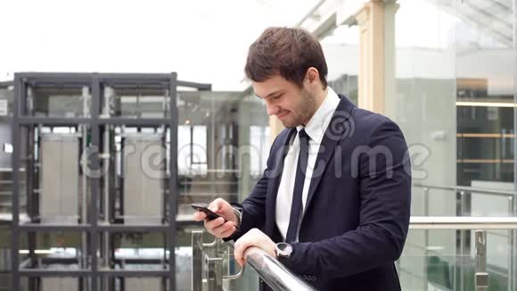 英俊的商人在办公室里使用智能手机视频的预览图