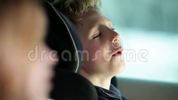 一家人开车去度假时汽车后座上的男孩特写镜头视频的预览图