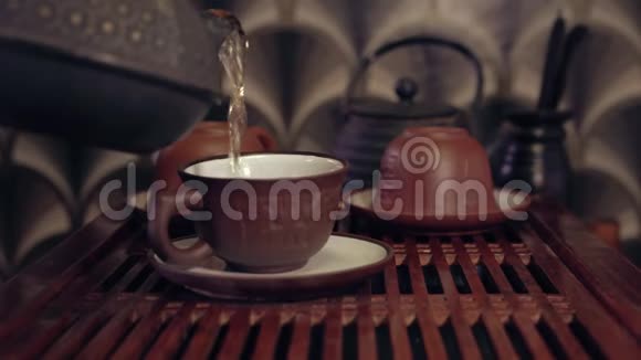 中国传统茶道的动作在一个杯子里用粘土茶壶倒茶两个茶壶放在软的焦点上视频的预览图