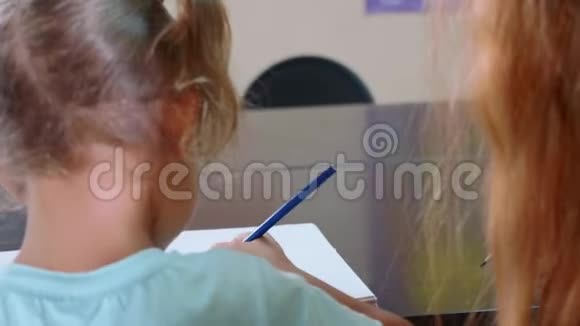 小可爱的女孩坐在教室里和老师一起在练习本上学习视频的预览图
