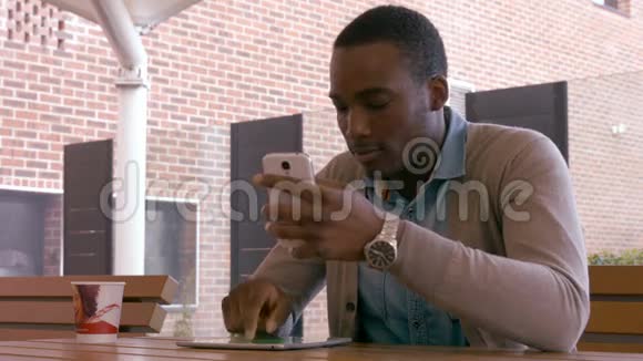 坐着的年轻人用智能手机和平板电脑视频的预览图