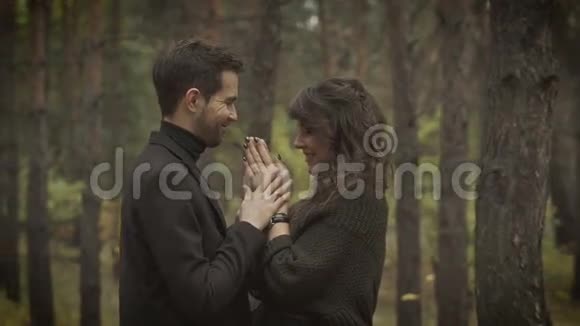 一对夫妇在森林里约会微笑的男人和女人站在树上互相看着微笑着视频的预览图