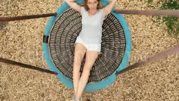 年轻女子在城市游乐园的吊床上荡秋千4k复制空间视频的预览图