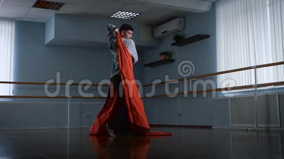 排练厅的年轻人排练跳舞作为陈述他用红色布料做旋转织物视频的预览图