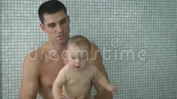 年轻的父亲和小儿子在儿童游泳池附近做运动视频的预览图
