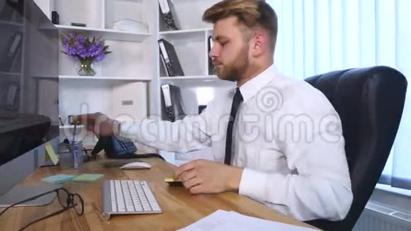年轻的商人坐在办公室的桌子旁在电脑上工作在笔记本上做笔记视频的预览图
