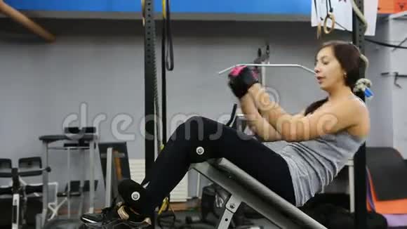 女人在健身房锻炼机器上练习仰卧起坐女人在举重凳上做仰卧起坐视频的预览图