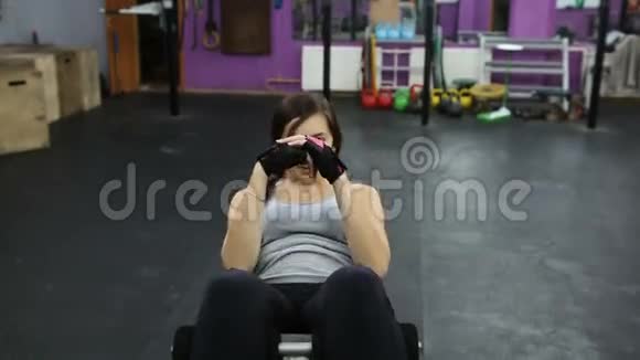 女人在健身房锻炼机器上练习仰卧起坐女人在举重凳上做仰卧起坐视频的预览图