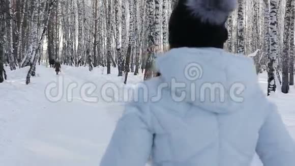 一个年轻女孩在冬林公园散步的特写镜头在移动中从后面射门视频的预览图