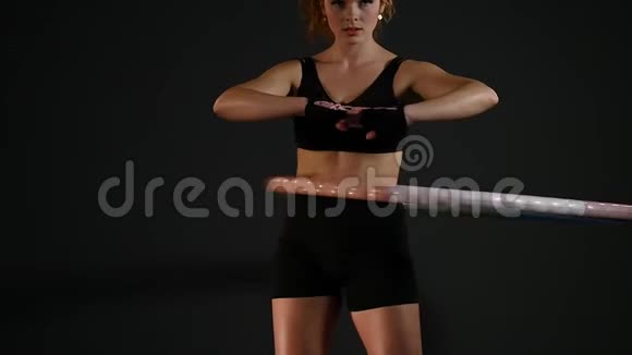 年轻女子在黑色背景下做呼啦圈锻炼视频的预览图