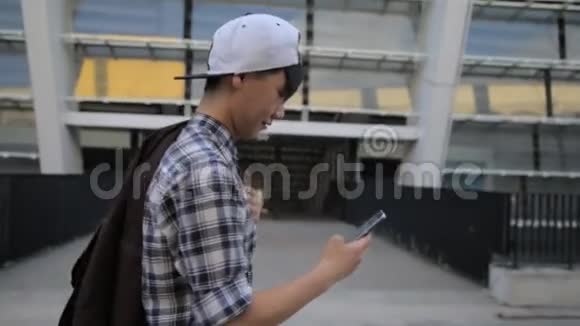 帅气亚洲学生男子打字智能手机市区夜光通讯技术4G接收短信视频的预览图