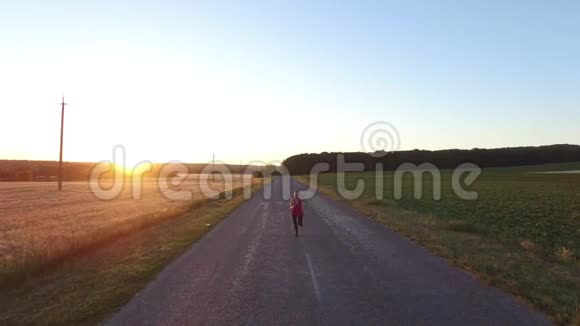 运动慢跑的女人在日落时在田野附近跑步视频的预览图