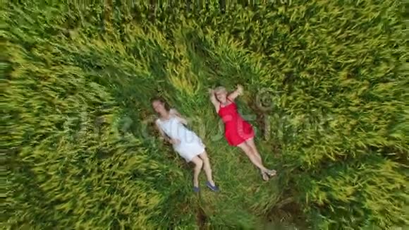两个金发碧眼的女人穿着一件红色和蓝色的衣服躺在地里视频的预览图