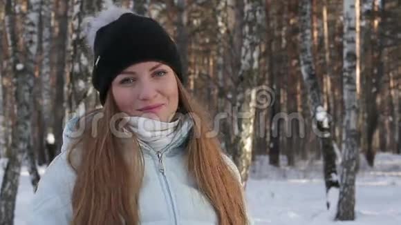 特写美女一边笑一边看镜头在冬林冬季森林的离焦背景视频的预览图