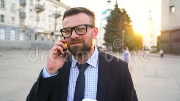 男人在智能手机上说话喝着咖啡走在街上慢动作视频的预览图