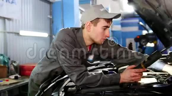 穿着工作服的机械师看着汽车引擎盖汽车维修视频的预览图