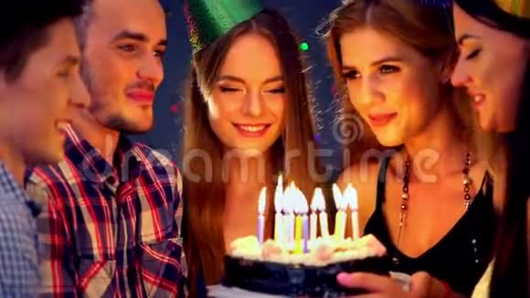 女孩和朋友一起庆祝生日在蛋糕上吹蜡烛4k视频的预览图