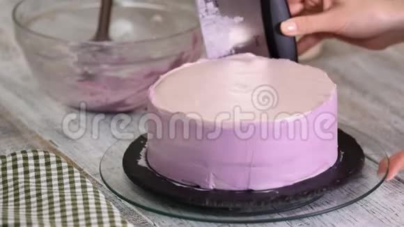 用紫色奶油盖装饰蛋糕的过程甜点师使用糕点抹刀将饼干奶油切等视频的预览图