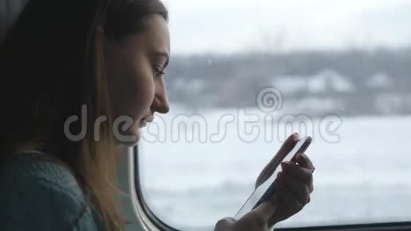 年轻女孩坐火车旅行用手机拍摄窗外的风景美丽美丽视频的预览图