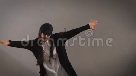 穿着白色衬衫黑色裤子夹克和黑色帽子的快乐时尚长发年轻女子正在跳跃展示着现代的气息视频的预览图