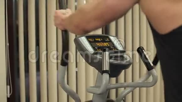 年轻的运动男子在健身房做椭圆机视频的预览图