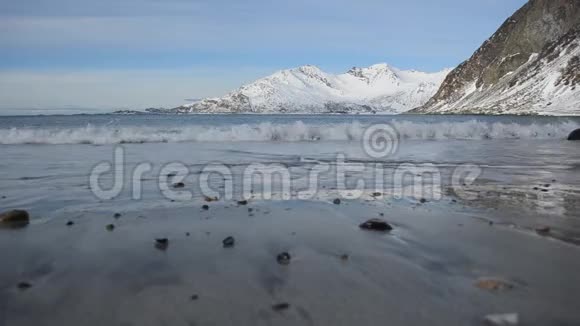清冽的寒潮冲击着深秋浅棕色的沙质海岸带着强大的雪山背景视频的预览图