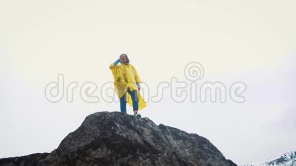 一个穿着黄色斗篷的年轻女孩沿着岩石跑一个旅行者正在山间旅行视频的预览图