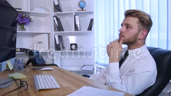 年轻的商人坐在办公室的桌子旁在电脑上工作在笔记本上做笔记视频的预览图