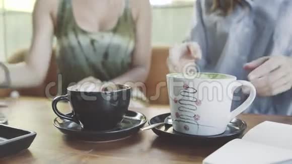 两个女人在咖啡馆里喝抹茶拿铁和咖啡视频的预览图