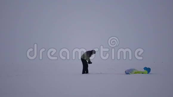 年轻人解开降落伞爬在雪地上4K视频的预览图