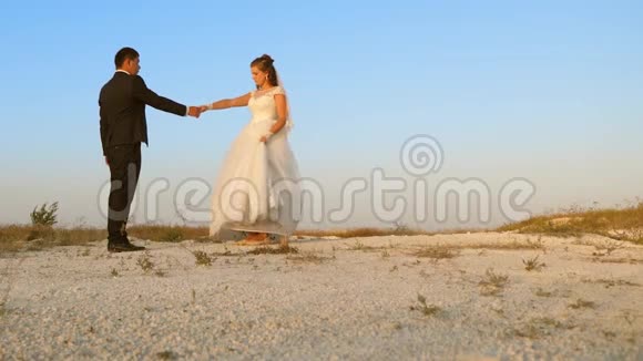 蜜月时的婚礼舞浪漫的男人和女人在沙滩上和天空跳舞视频的预览图
