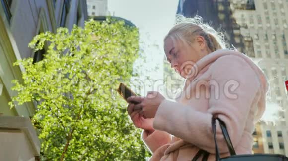 年轻的商务女性在一个大城市使用智能手机在城市景观的背景下摩天大楼这就是视频的预览图