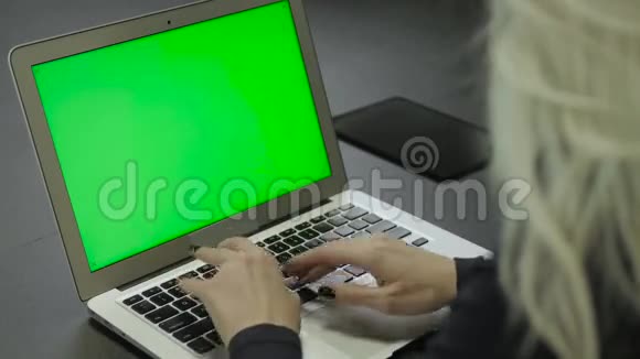 笔记本电脑键盘上的特写镜头打字带有绿色屏幕的笔记本电脑视频的预览图