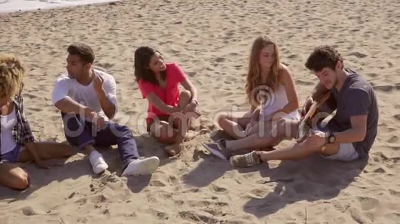 五个英俊的朋友坐在沙滩上视频的预览图