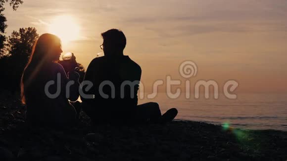 夕阳西下一对夫妇带着酒杯在湖边放松高加索女人和亚洲男人视频的预览图