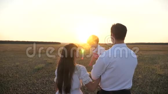 一家人在日落时和婴儿玩日落时分爸爸和妈妈和她的女儿抱在怀里散步父亲视频的预览图