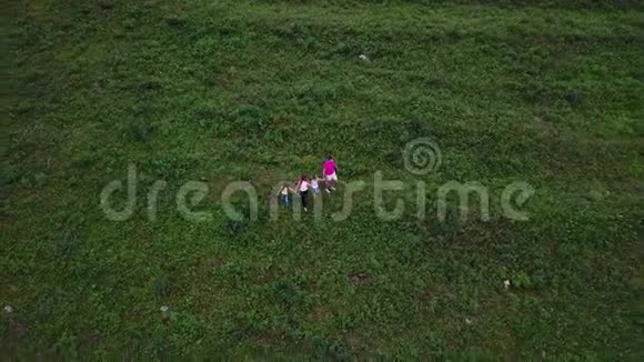 空中飞行幸福的家庭去野营了父母和他们的孩子一起走在山脚下的草地上视频的预览图