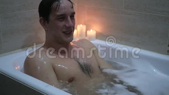 一个年轻人坐在浴室里用泡沫和竖起大拇指动作缓慢视频的预览图
