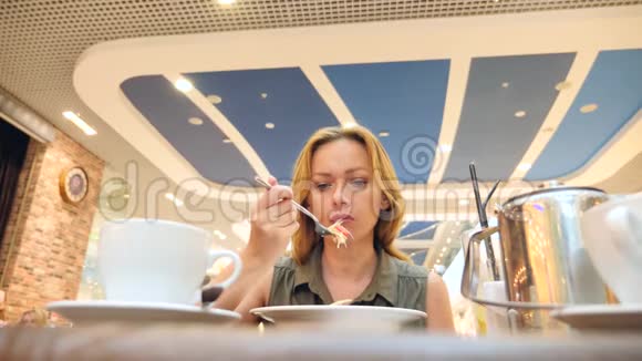 女人吃得筋疲力尽在咖啡馆里吃卷心菜沙拉4K慢动作复制空间视频的预览图