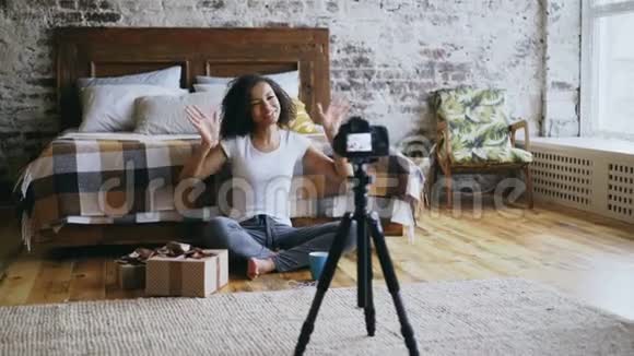 年轻快乐的混血女孩录制视频博客关于在家包装圣诞礼物盒视频的预览图