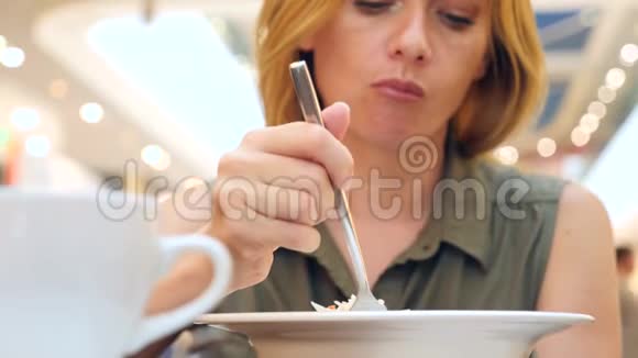 女人吃得筋疲力尽在咖啡馆里吃卷心菜沙拉4K慢动作复制空间视频的预览图