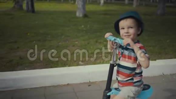 两岁快乐的小男孩在夏天的公园里骑摩托车视频的预览图