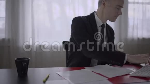 一个穿着夹克的人在办公桌上写文件视频的预览图