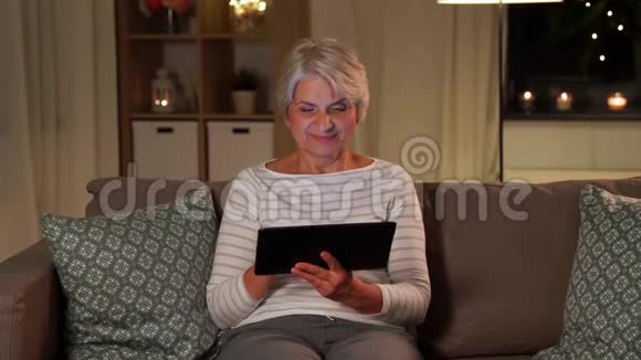 晚上在家玩平板电脑的快乐高级女性视频的预览图