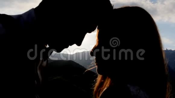 一对相爱的夫妇在夕阳背景下的剪影群山视频的预览图